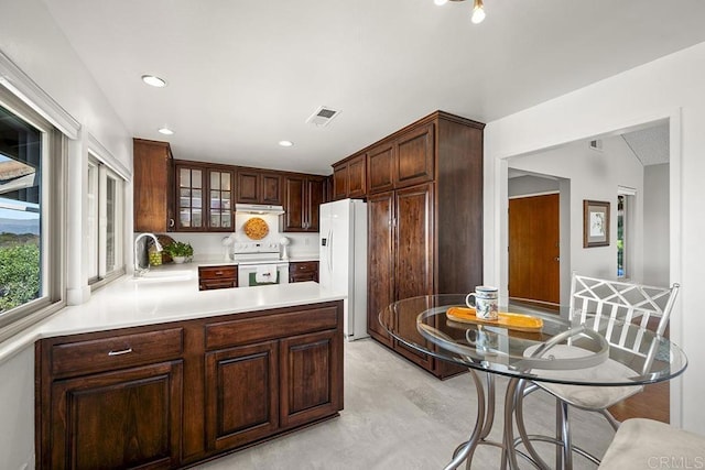 kitchen featuring white appliances, kitchen peninsula, sink, and dark brown cabinets