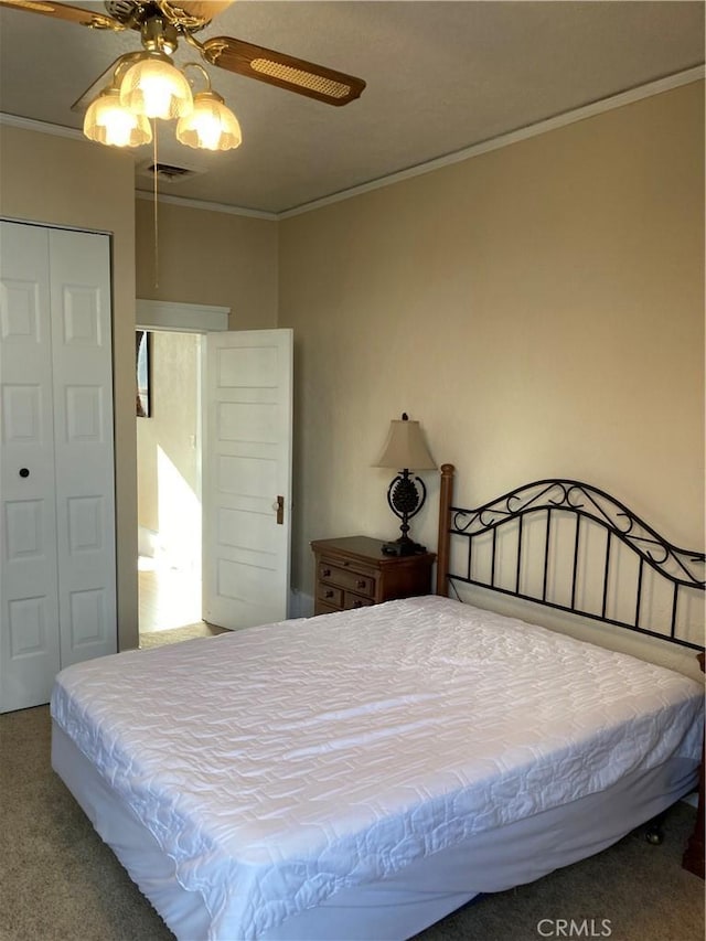 carpeted bedroom featuring ceiling fan, a closet, and crown molding