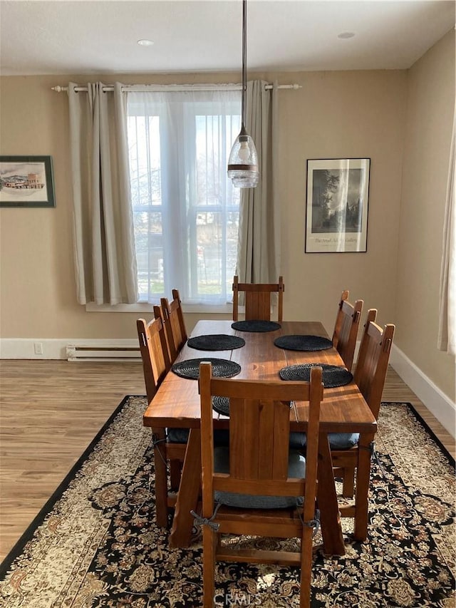 dining area featuring plenty of natural light, a baseboard radiator, and hardwood / wood-style floors