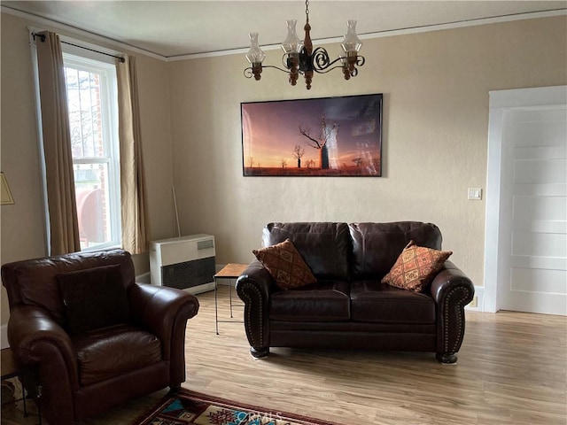 living room with an inviting chandelier, ornamental molding, heating unit, and hardwood / wood-style flooring