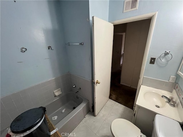 bathroom with a washtub, toilet, vanity, and tile patterned flooring