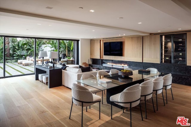 dining area featuring beam ceiling, a wall of windows, and light hardwood / wood-style flooring