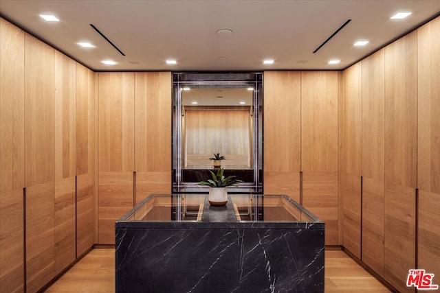 interior space featuring light brown cabinets, light hardwood / wood-style flooring, and wood walls