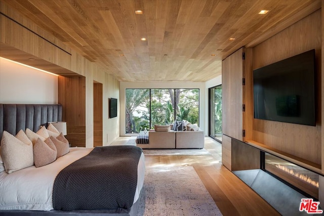 bedroom with light wood-type flooring, wood ceiling, and wooden walls