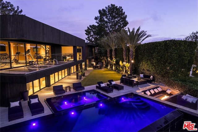 pool at dusk featuring an in ground hot tub and a patio