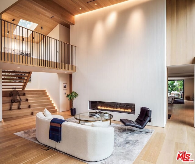 living room with light hardwood / wood-style floors, a high ceiling, and wood ceiling