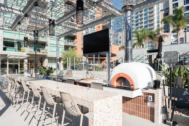 view of patio / terrace featuring a brick fireplace, exterior bar, and area for grilling