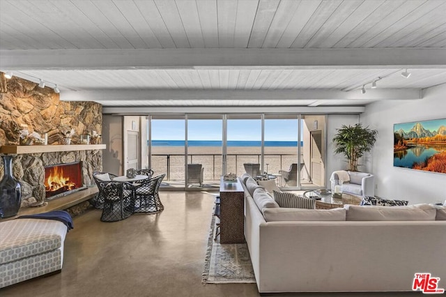 living room with floor to ceiling windows, track lighting, a fireplace, concrete flooring, and beamed ceiling