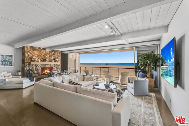 living room with track lighting, beamed ceiling, and a fireplace