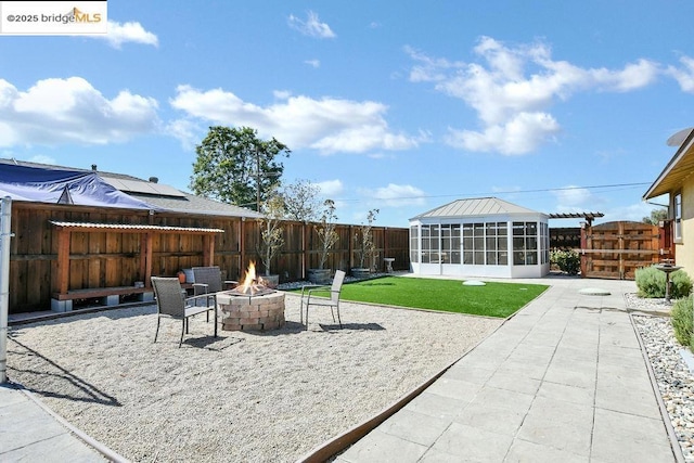 view of patio / terrace featuring an outdoor fire pit and a sunroom