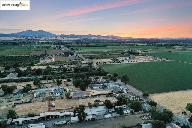 aerial view at dusk featuring a water and mountain view and a rural view