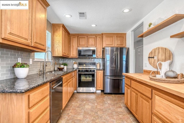 kitchen featuring tasteful backsplash, sink, appliances with stainless steel finishes, and wood counters