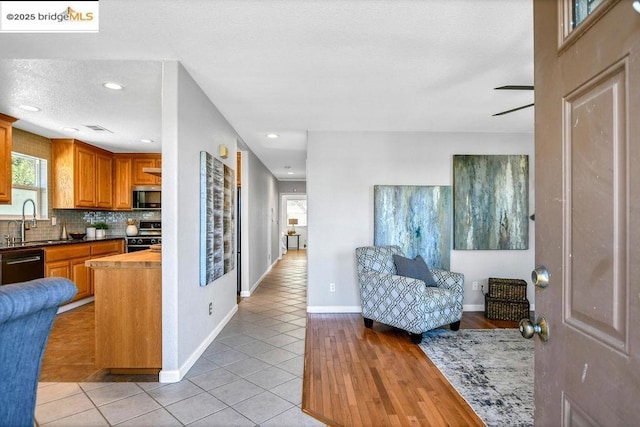 kitchen featuring backsplash, black appliances, sink, light tile patterned flooring, and wood counters