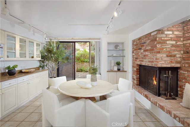 dining area with a brick fireplace, light tile patterned flooring, and built in features