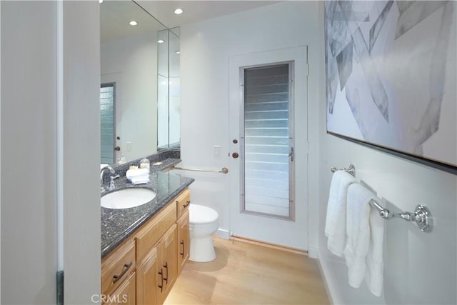 bathroom with toilet, vanity, and hardwood / wood-style flooring