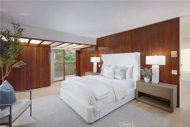 bedroom with access to exterior, wood walls, and light wood-type flooring