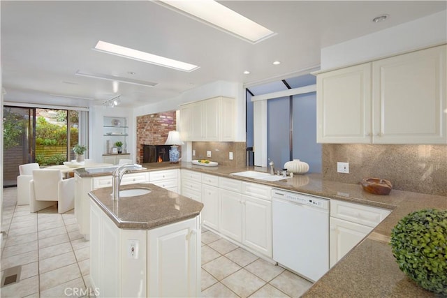 kitchen featuring kitchen peninsula, sink, white dishwasher, and decorative backsplash