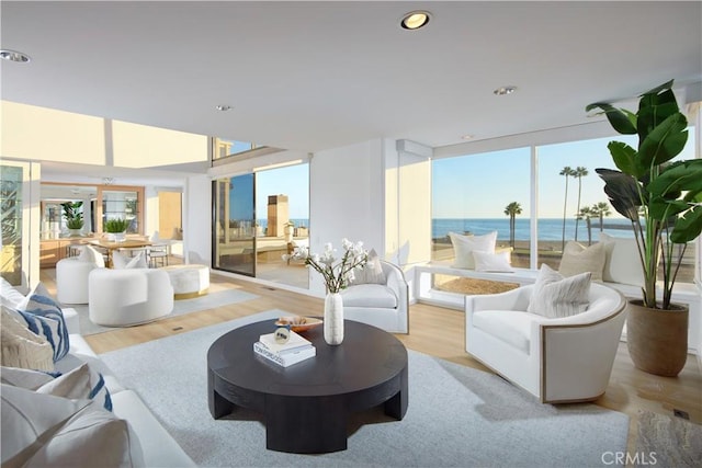 living room featuring a water view, floor to ceiling windows, and light hardwood / wood-style flooring