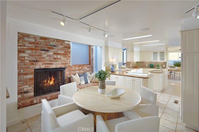 tiled dining area featuring a brick fireplace and sink