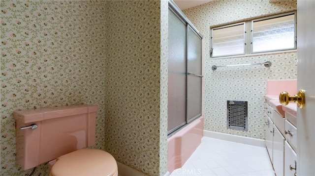 full bathroom featuring toilet, bath / shower combo with glass door, tile patterned flooring, and vanity