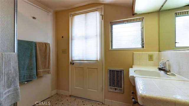 interior space with light tile patterned floors, heating unit, and sink