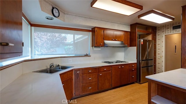 kitchen with sink, white gas cooktop, stainless steel fridge, and light wood-type flooring