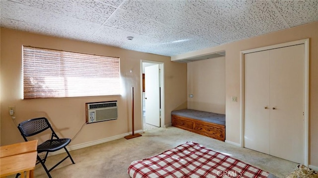 carpeted bedroom with a paneled ceiling and an AC wall unit