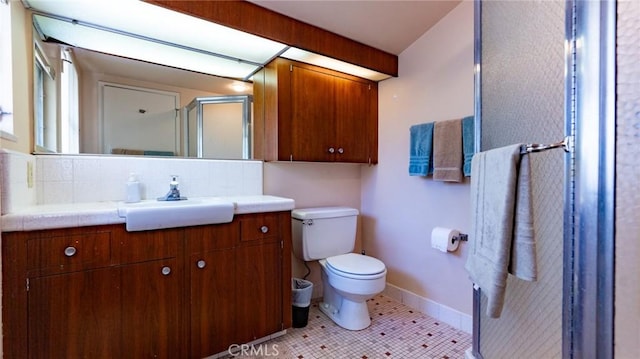 bathroom featuring toilet, backsplash, tile patterned flooring, walk in shower, and vanity