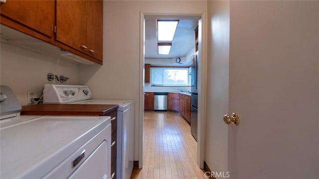 laundry area featuring cabinets, separate washer and dryer, and light hardwood / wood-style floors