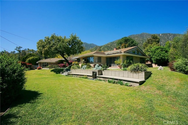 rear view of property featuring a mountain view and a lawn