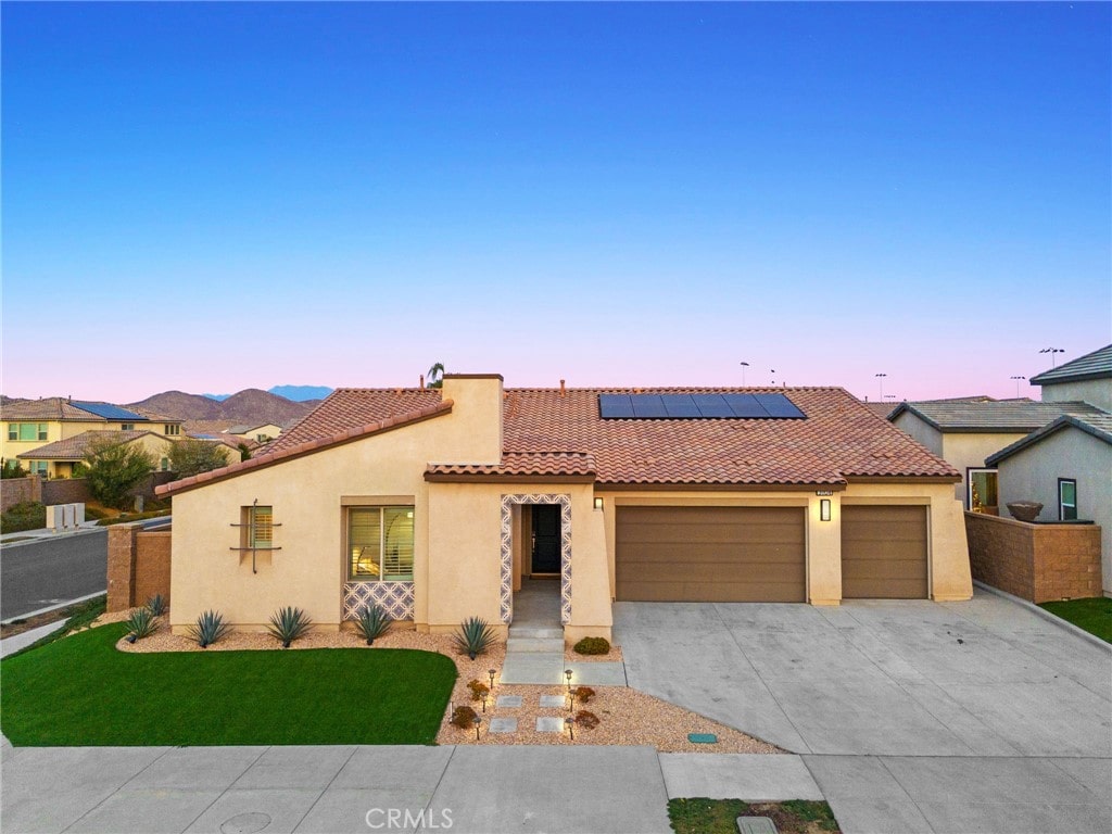 mediterranean / spanish-style home with solar panels and a garage