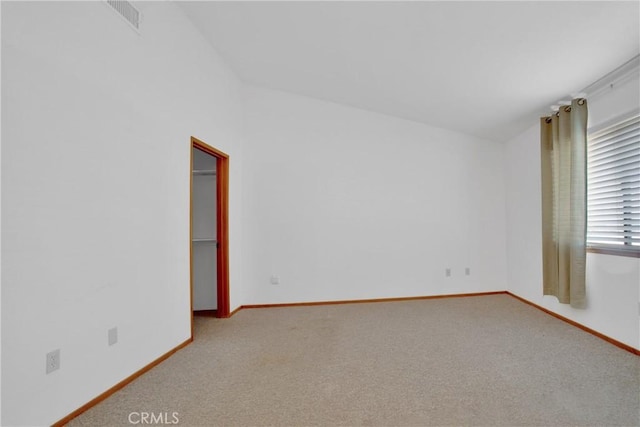 carpeted spare room with vaulted ceiling