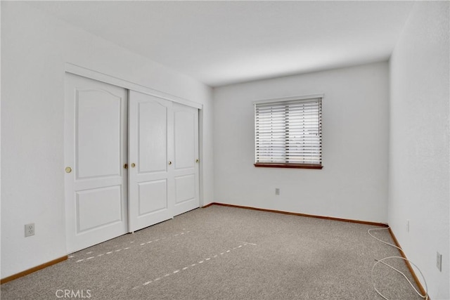 unfurnished bedroom featuring light colored carpet and a closet