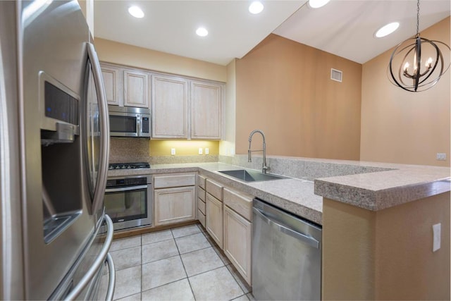 kitchen featuring an inviting chandelier, appliances with stainless steel finishes, light brown cabinetry, and sink