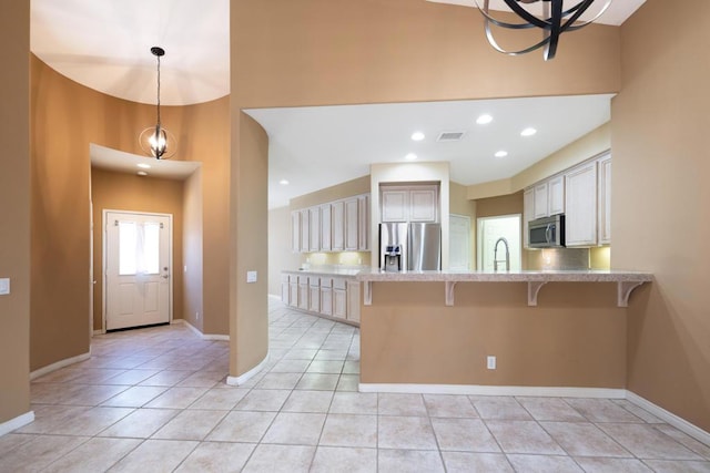 kitchen with stainless steel appliances, a notable chandelier, a kitchen breakfast bar, decorative light fixtures, and light tile patterned flooring