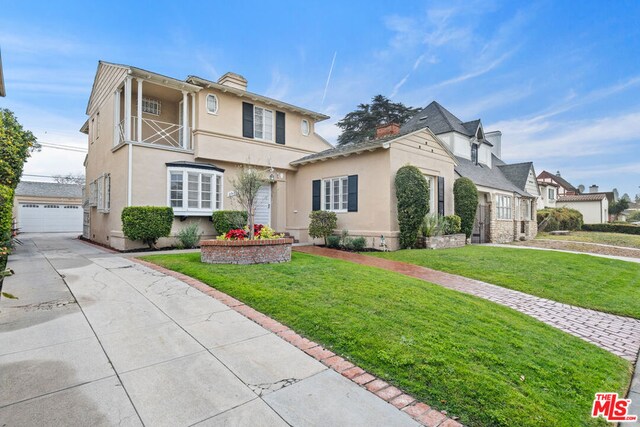 view of front property featuring a balcony, a front lawn, and a garage