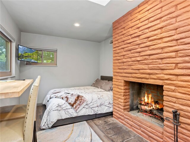 bedroom featuring a large fireplace and wood-type flooring