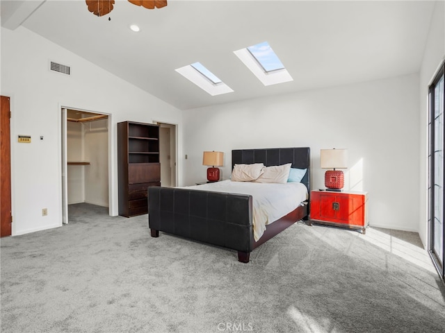 bedroom featuring light carpet, ceiling fan, a closet, vaulted ceiling, and a walk in closet