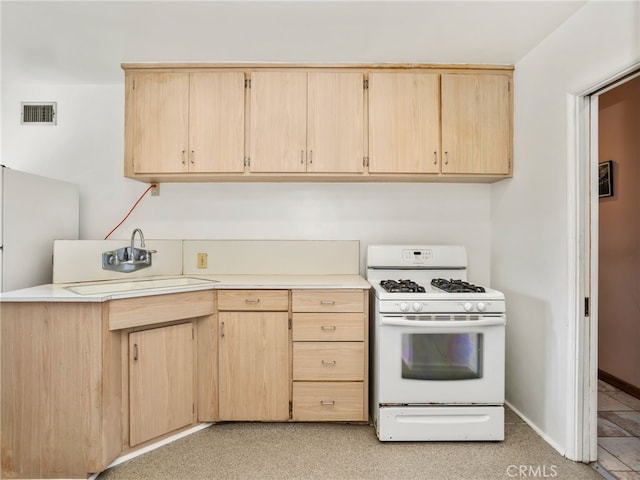 kitchen with gas range gas stove, light brown cabinetry, and sink