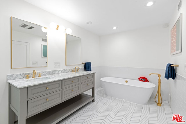 bathroom with vanity, tile patterned flooring, tile walls, and a tub