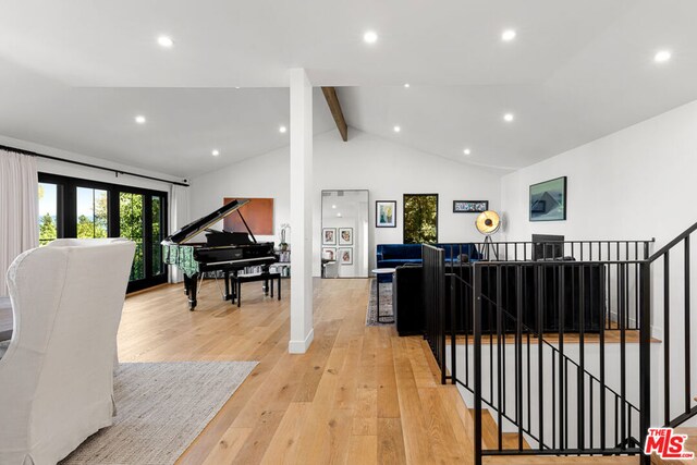 living room featuring light wood-type flooring and vaulted ceiling with beams