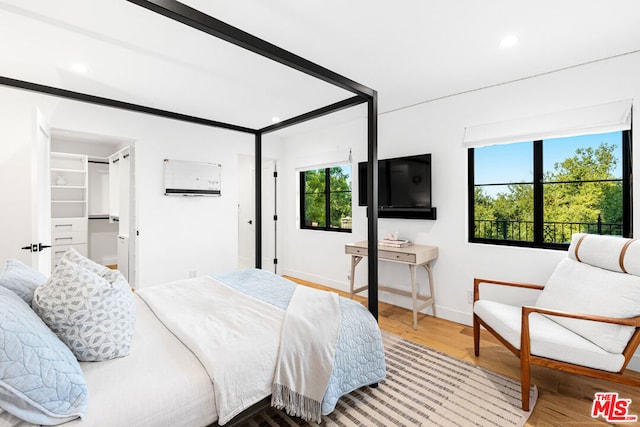 bedroom featuring a walk in closet, multiple windows, and hardwood / wood-style floors