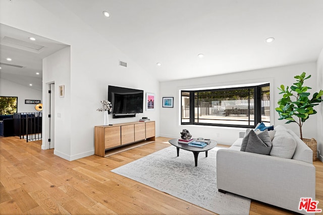 living room with light hardwood / wood-style floors and high vaulted ceiling