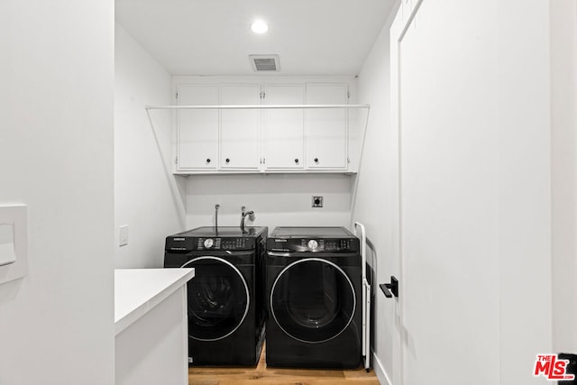 washroom with cabinets, light hardwood / wood-style floors, and washer and clothes dryer