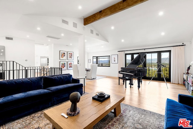 living room with lofted ceiling with beams, light wood-type flooring, and plenty of natural light