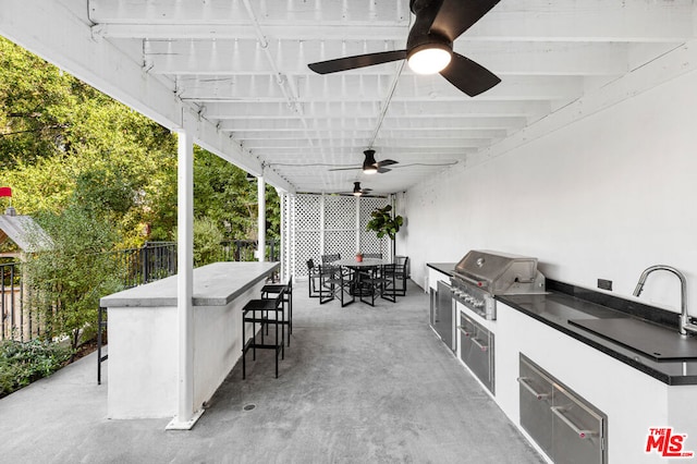 view of patio / terrace with ceiling fan, an outdoor wet bar, an outdoor kitchen, and area for grilling