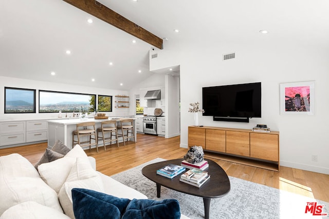 living room with high vaulted ceiling, beam ceiling, and light wood-type flooring