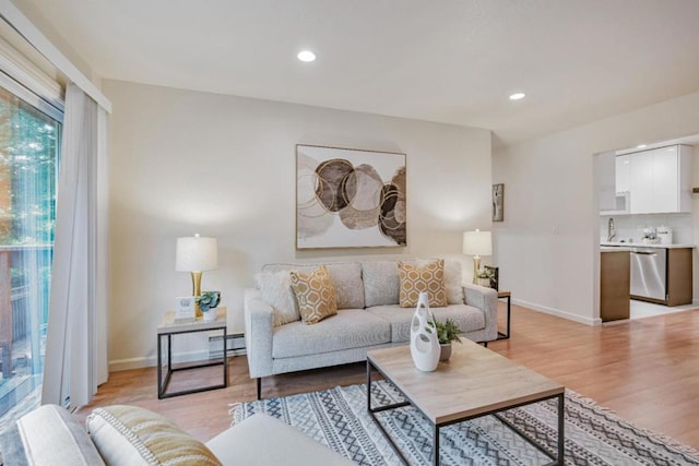 living room with light hardwood / wood-style flooring, a baseboard heating unit, and sink