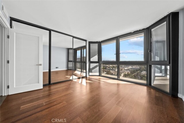 unfurnished room featuring expansive windows and hardwood / wood-style flooring