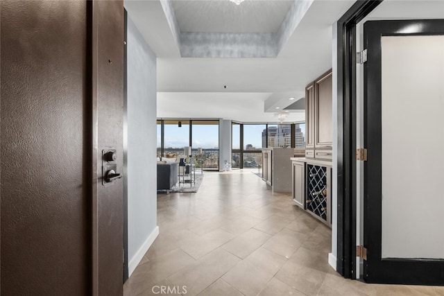 hallway featuring a wall of windows and a raised ceiling